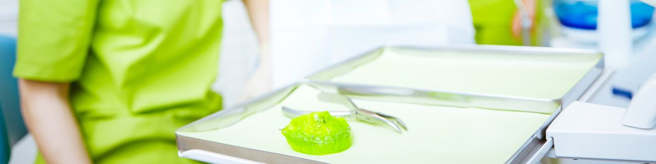 Ein medizinisches Tablett mit Instrumenten und einer grünen Substanz liegt bereit für eine Behandlung.