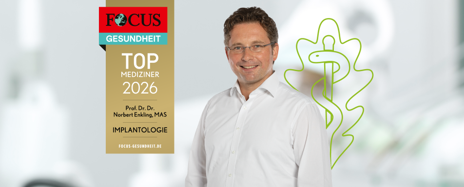 Ein lächelnder Mann steht vor einem FOCUS-Gesundheitssiegel, das ihn als Top-Mediziner 2026 in der Implantologie auszeichnet.