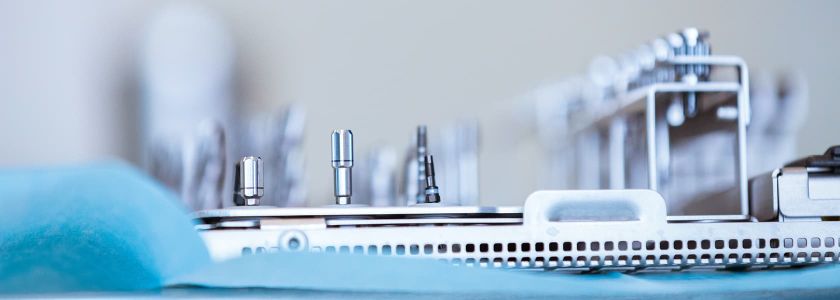 Nahaufnahme von mehreren zahnärztlichen Instrumenten, die ordentlich angeordnet sind. Der Hintergrund ist unscharf, der Fokus liegt auf den glänzenden Werkzeugen im Vordergrund.